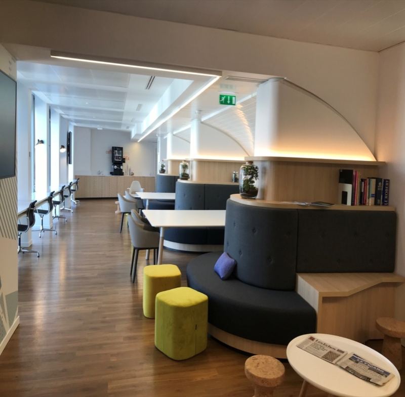 Espace détente aménagé sous une voûte façon station de métro, banquettes et tabourets colorés