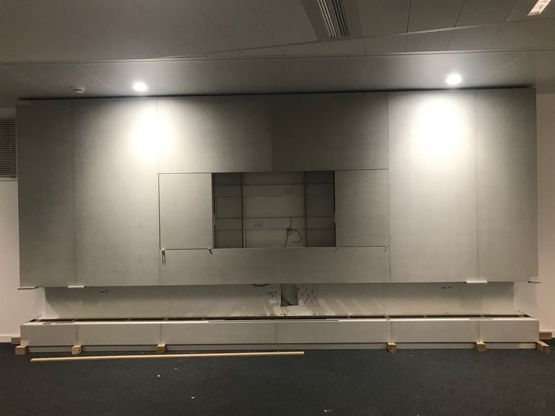 Meuble télé intégré dans un habillage de panneaux effet béton
